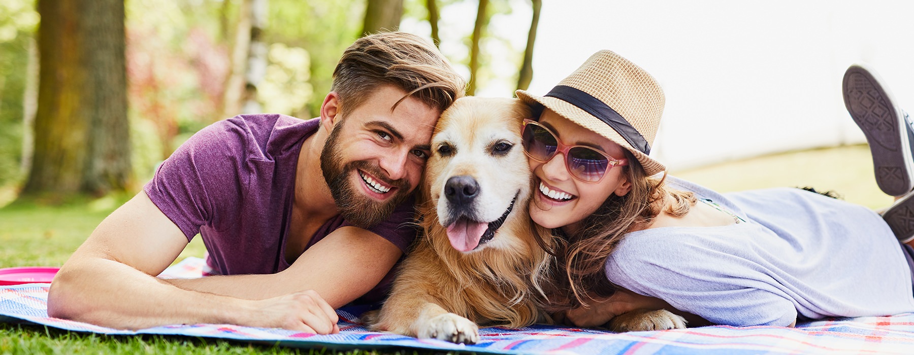 Couple laying on the grass with their dog 
